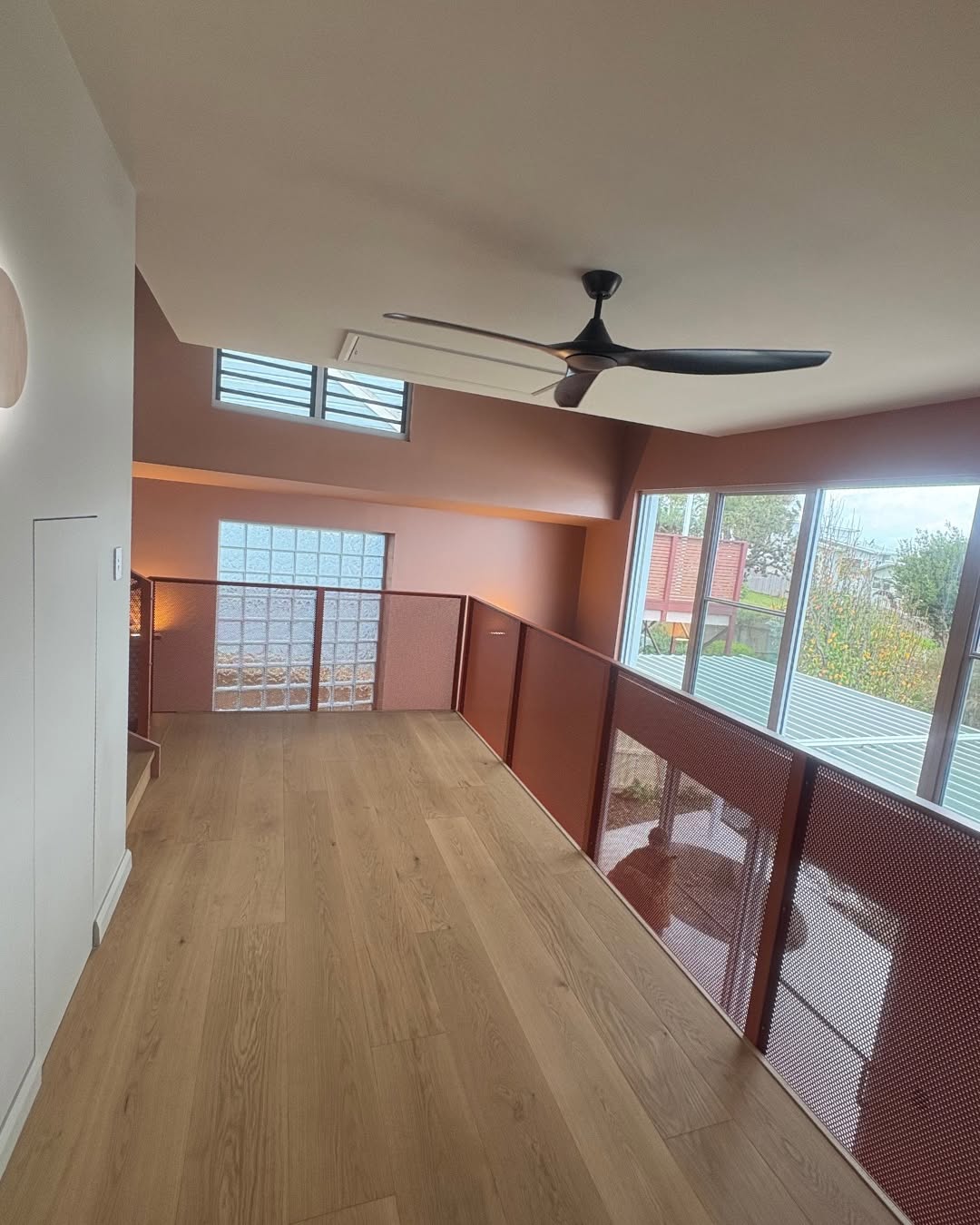 Completed upper level interior of a custom home built by CKS Projects, showing a timber mezzanine floor, perforated steel balustrade, clerestory windows, and large glazed openings, illustrating the quality of construction that Class 2 building certification verifies at each critical stage