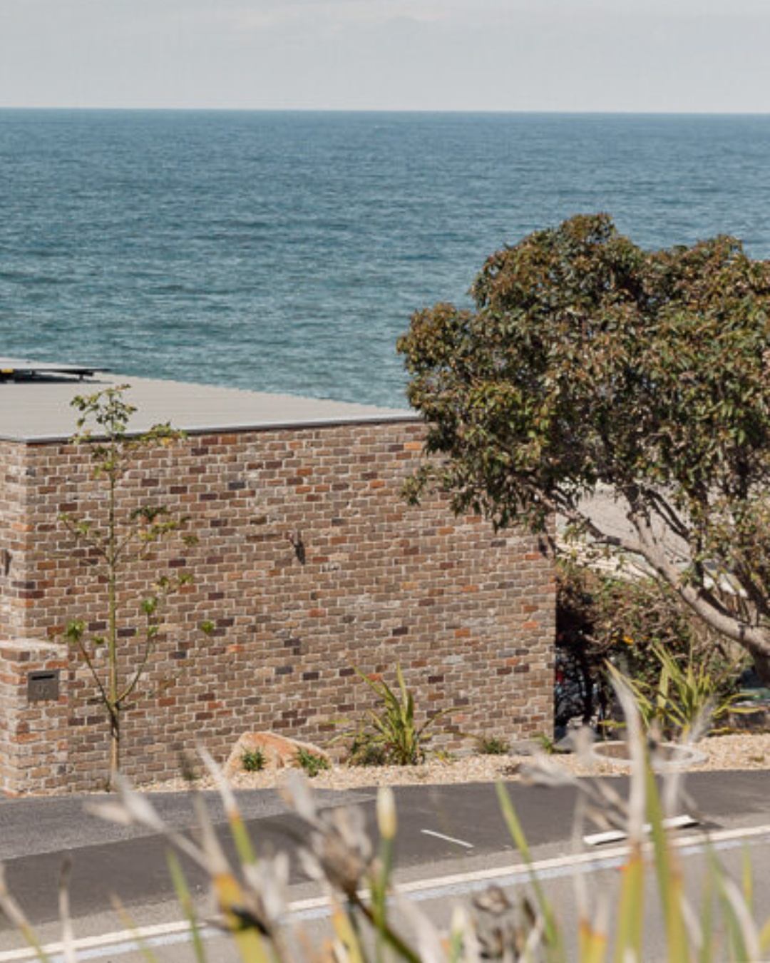 Coastal residential build with recycled brick wall and ocean view — the type of complex Illawarra site where transparent preliminary costing matters most