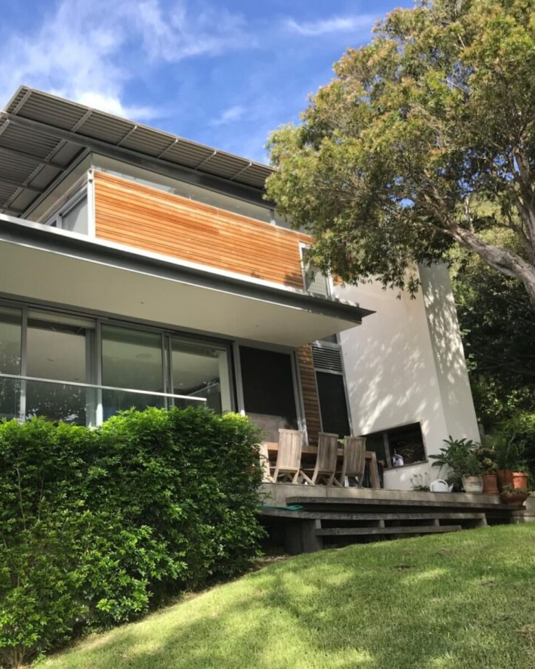Completed custom home exterior with rendered facade, timber louvres, and outdoor deck — the result of thorough pre-construction cost planning