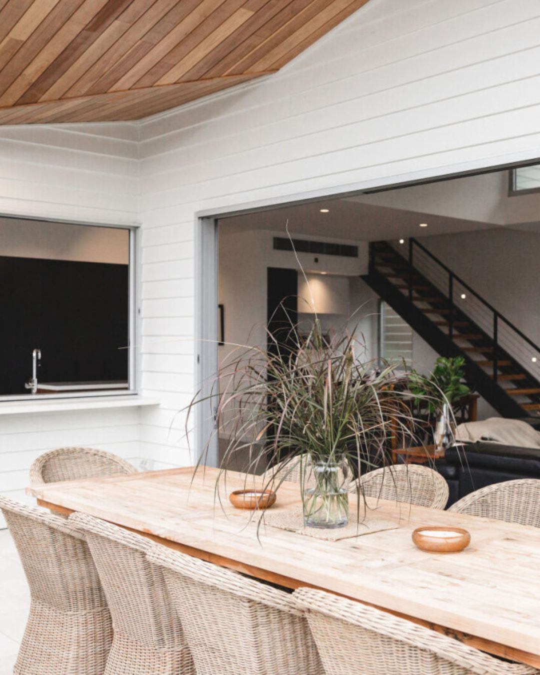Completed outdoor alfresco and dining area of a CKS Projects custom home in the Illawarra, featuring a timber ceiling, white weatherboard cladding, and a view into the open living interior, showing the quality outcome that a council-approved, builder-led project delivers