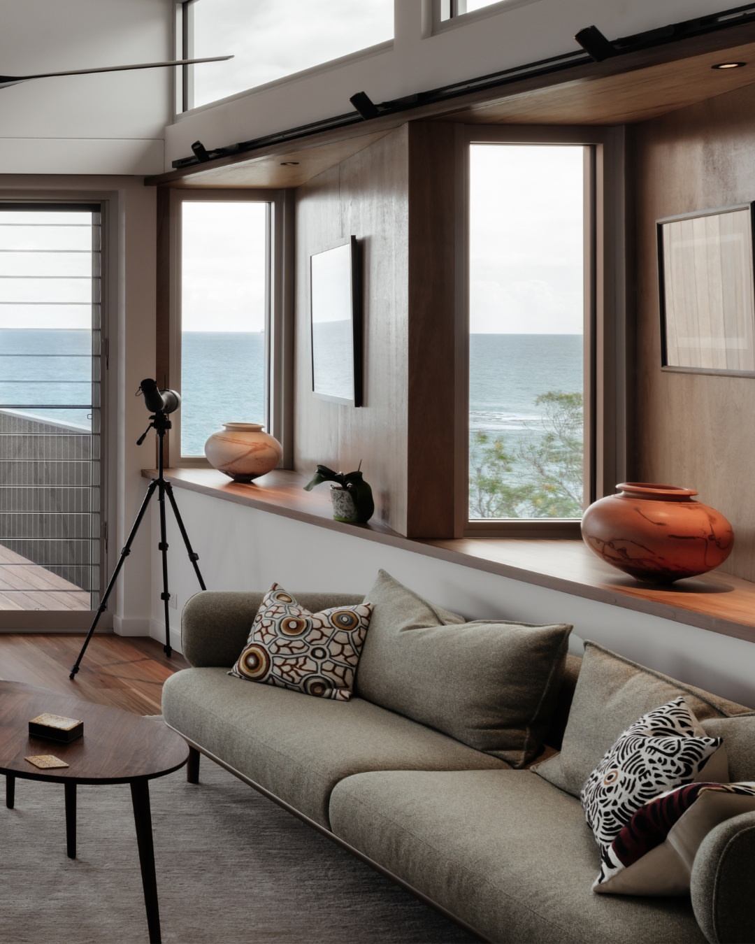 Interior living room of a completed coastal CKS Projects home with wide casement windows framing Illawarra ocean views, warm timber flooring, and natural light filling the space, demonstrating the year-round comfort and connection to place that passive solar design delivers