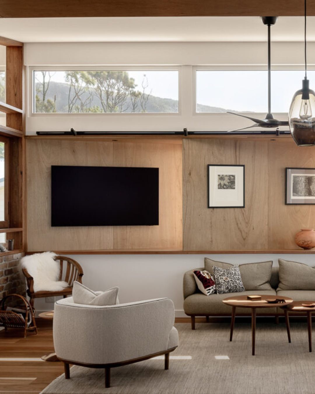 Warm, finished living room interior of a custom CKS Projects home in the Illawarra, featuring timber wall panelling, clerestory windows with mountain views, and natural material finishes, showing the quality living outcome that clear Pre-DA planning makes possible