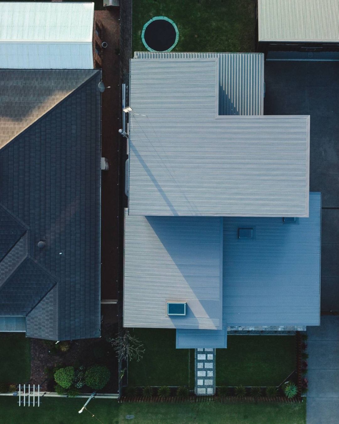 Aerial drone view of a modern home on a narrow infill residential block, showing site positioning, roof form, and relationship to neighbouring properties