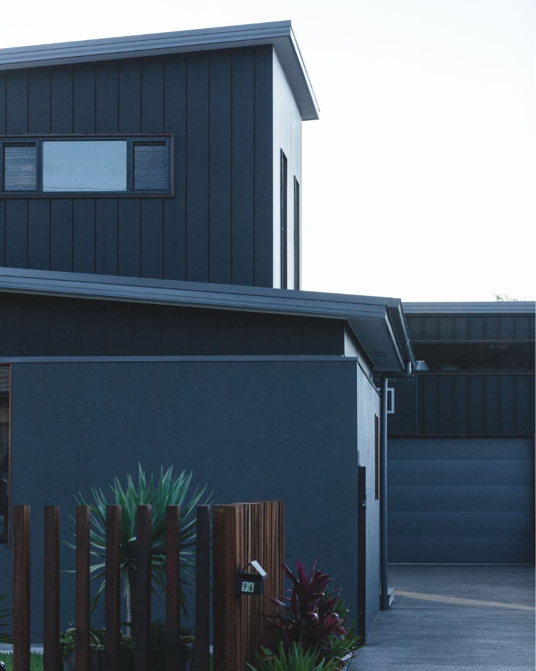 Completed custom dual occupancy development in the Illawarra showing two attached townhouse dwellings with dark vertical cladding, separate entries, private fencing, and landscaping, representing a builder-led CKS Projects multi-residential outcome