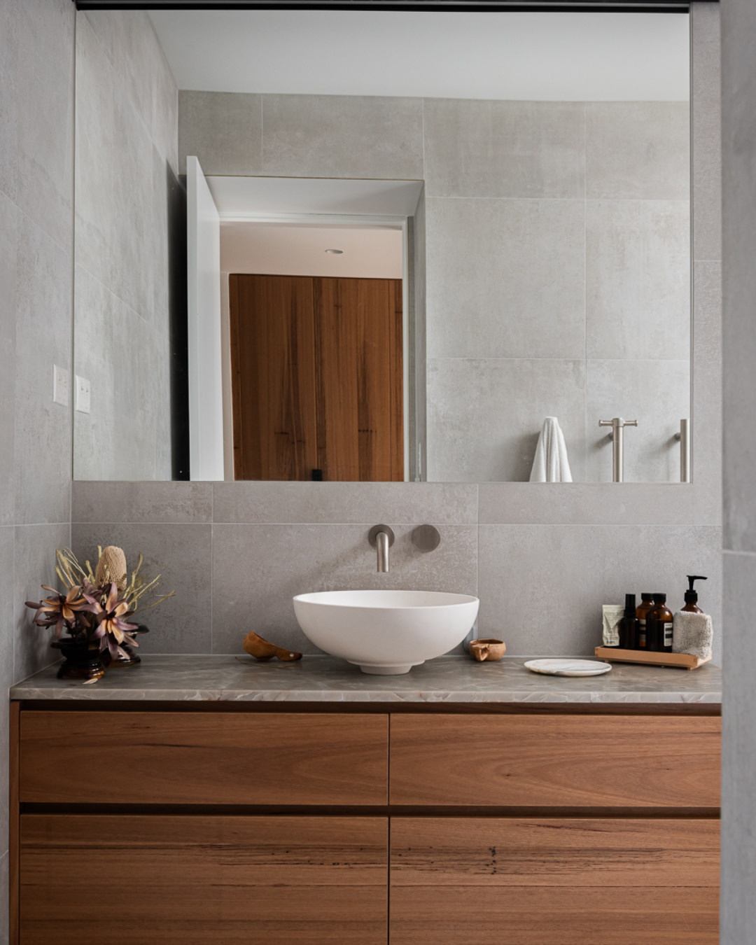 High-specification bathroom interior in a completed CKS Projects townhouse showing a vessel bowl basin on a timber vanity, stone-effect wall tiles, brushed nickel tapware, and custom joinery, demonstrating the premium finish standard delivered across Illawarra townhouse builds