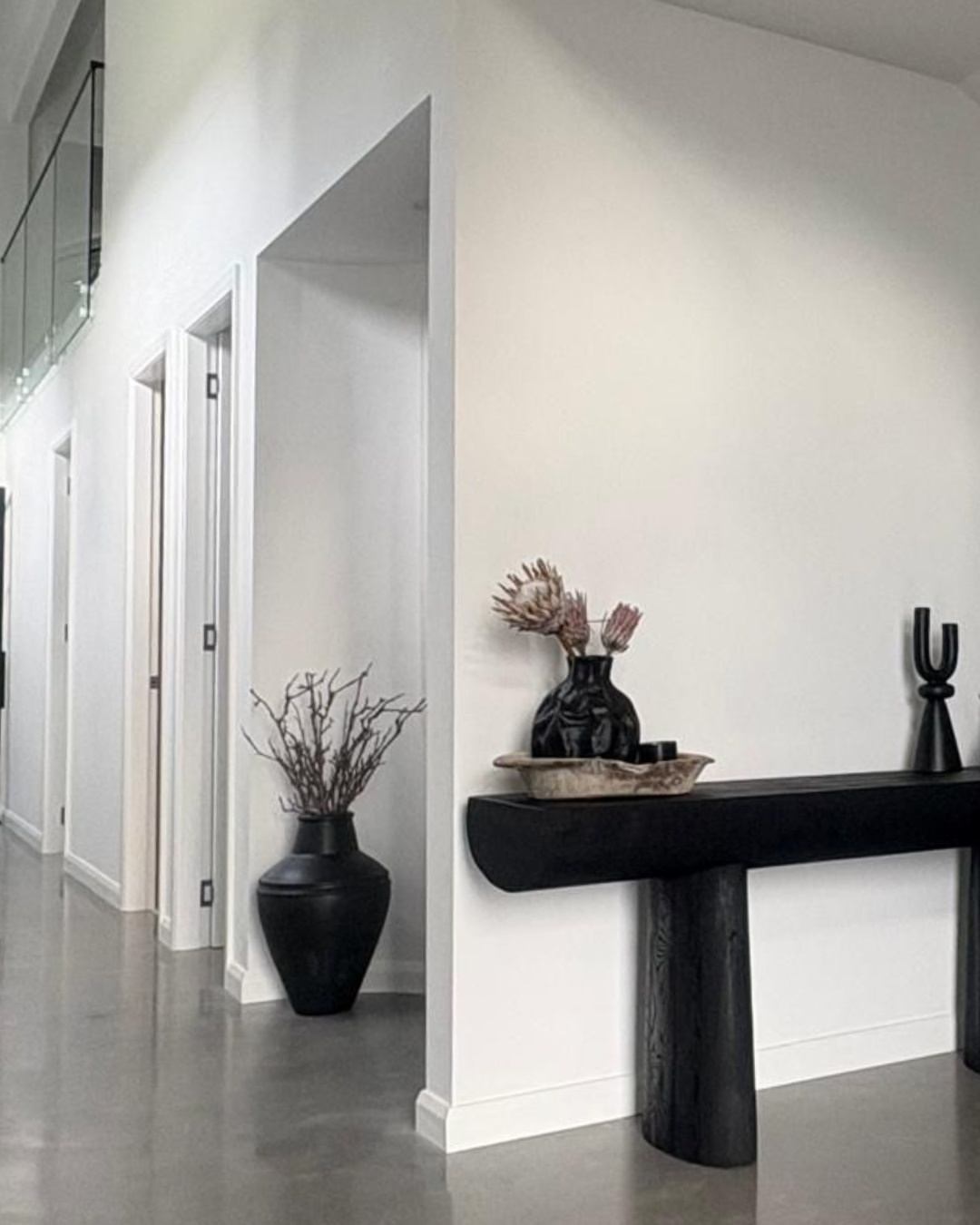 Elegant residential hallway interior with polished concrete floor, white walls, and glass balustrade