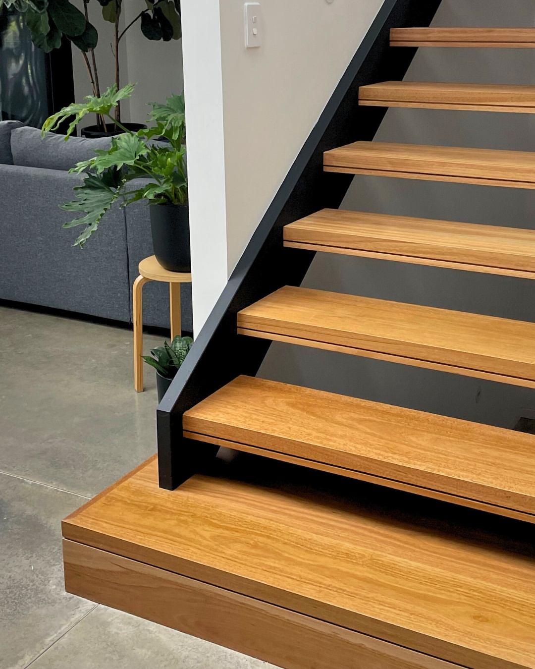 Close detail of timber stair treads with black steel stringer on polished concrete floor